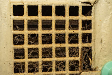 An old ventilation grill, clogged with cobwebs and mildew. Clogged and dirty ventilation system.の写真素材
