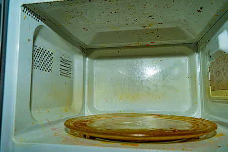 Microwave contaminated during operation. Residues and particles of food on the surface of the microwaveの写真素材