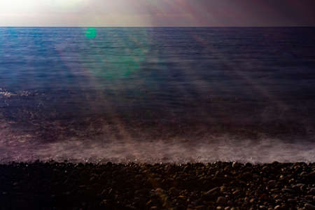 The sea coast in the rays of the setting sun. The effect of film photography.