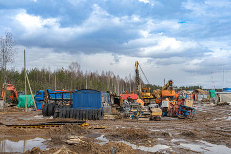 Construction machinery in a construction parking lot, mud and slush on the road. Warehouse of spare...