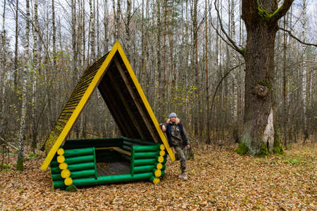 girl in the autumn forest next to gazebo made of logsの写真素材