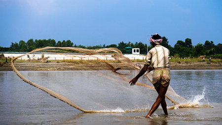 Ishwardi, Bangladesh - 10/10/2022: bengal fisherman casts net into river. catching fish with netのeditorial素材