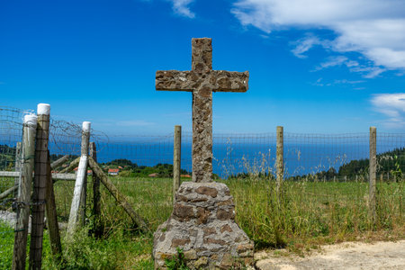 Cross made of stone against the backdrop of the Atlantic Ocean, the road leading to the cross, let St. James, Camino de Santiago, Basque Country, Spainの写真素材