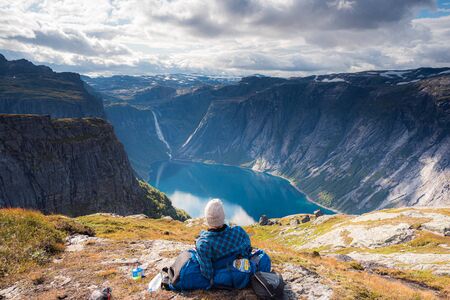 02/09-17, Tyssedal, Norway. A man is taking a break from the hike to the cliff of Trolltunga enjoying the view of the reservoir lake ringedalsvatnet.の写真素材