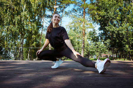 mom and daughter in sportswear on a sunny summer day on the embankment in the park doing fitnessの写真素材