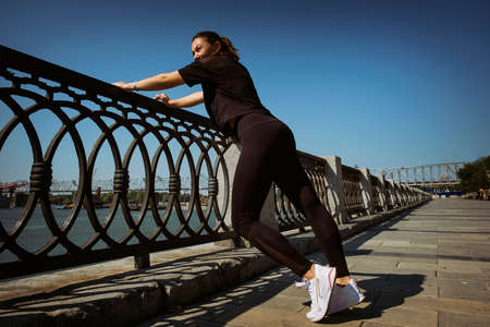 mom and daughter in sportswear on a sunny summer day on the embankment in the park doing fitnessの写真素材