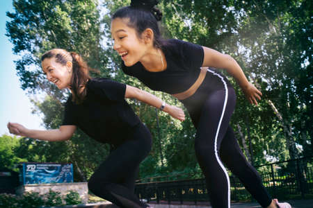 mom and daughter in sportswear on a sunny summer day on the embankment in the park doing fitnessの写真素材