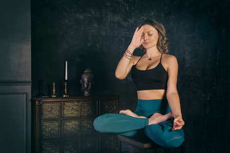 a charming girl in a sports uniform does yoga in an old room with a fireplace and candles