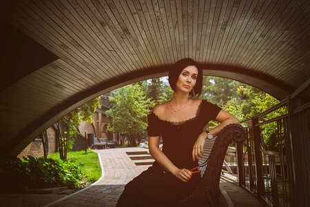 a pretty charming middle-aged woman in a black dress, hat and sunglasses strolls through the city...