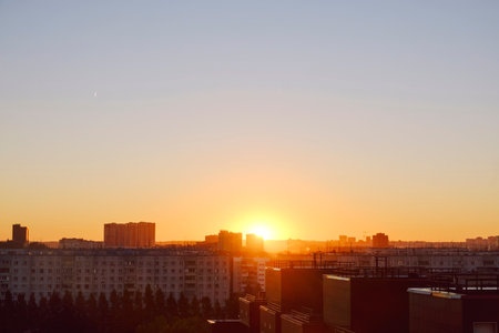 the sun rises above the skyline illuminating the houses and streets of the sleeping cityの写真素材
