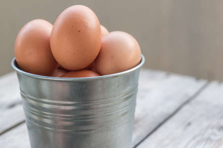 eggs in metallic bucket on woodの写真素材