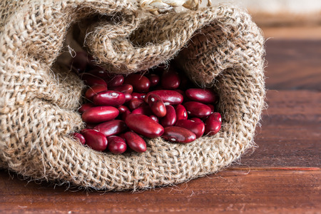 closeup red kidney bean in gunny bag on wood tableの写真素材