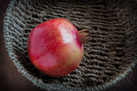 pomegranate in basket on wood tableの写真素材