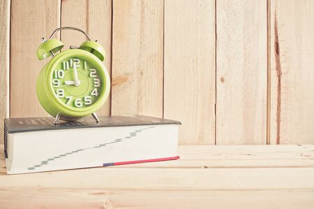 clock and dictionary on wooden table over wood background Still life styleの写真素材