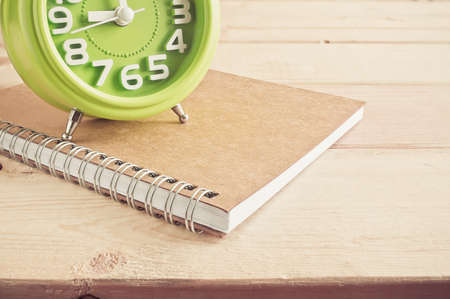 Alarm clock and  notebook on wooden table over wood background Still life styleの写真素材