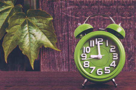 Clock on Wooden Floor with Leaf and Wood Background 