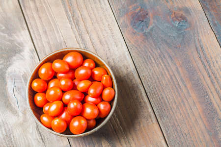 Fresh cherry tomato in wood bowl on wood backgroundの写真素材