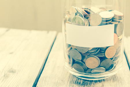 Money jar with coins on wood table , Saving Concept and Retro Vintage Styleの写真素材