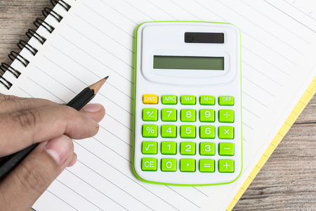 Hand Hold Pencil with Calculator Placed on Notebookの写真素材