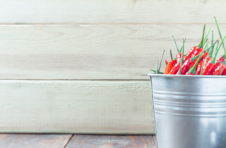 red chili peppers in aluminium bucket on wood tableの写真素材