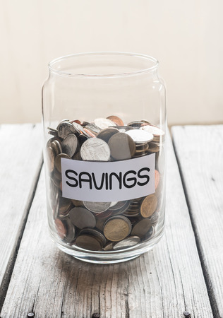 Money jar with coins on wood table , Saving Conceptの写真素材