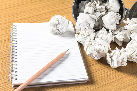Pencil and spiral notebook with crumbled paper on wooden desk , Creativity crisis solution conceptの写真素材