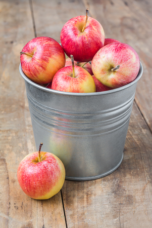 Apples in bucket on wood tableの写真素材
