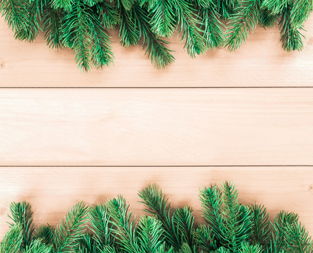 Christmas tree twigs of spruce on a wood background arranged in border pattern