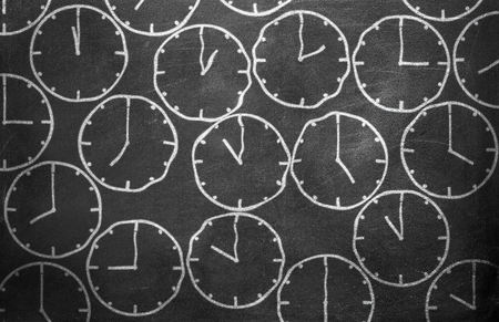 Clock from chalk on black chalkboard background textureの写真素材