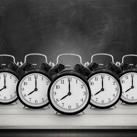Five of vintage alarm clock on wood table desk over chalkboard background  alarm clock show 8 oclockの写真素材