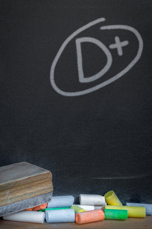 Colorful of chalk on wood table over grade d plus on black chalkboard backgroundの写真素材