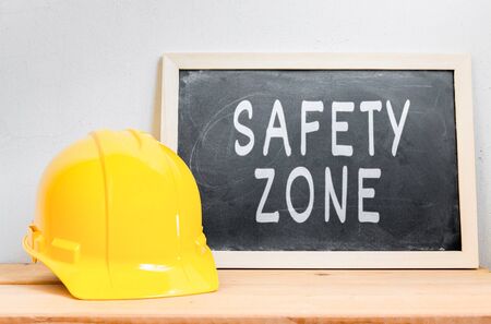 Helmet safety with chalkboard  SAFETY ZONE  on wood table , Safety First Conceptの写真素材