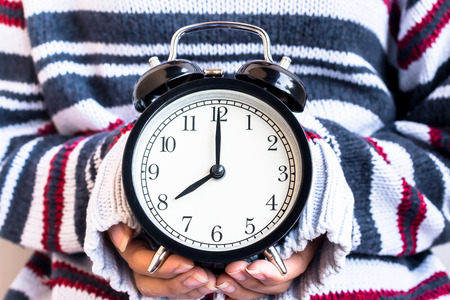 Women hand hold a vintage alarm clock