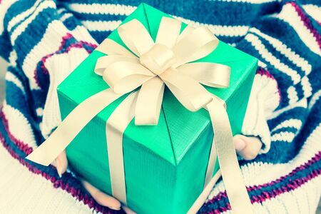 Women hand hold a green gift box with gold ribbon in vintage toneの写真素材