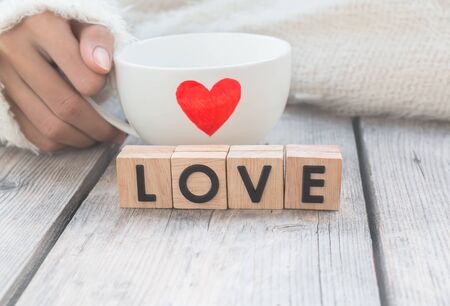 Woman hold cup of love with words "Love" from wooden cubes  - people, relationship and love conceptの写真素材