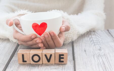 Woman hold cup of love with words "Love" from wooden cubes  - people, relationship and love conceptの写真素材