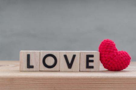 "Love" in wooden cube with red heart shape silk on wood tableの写真素材