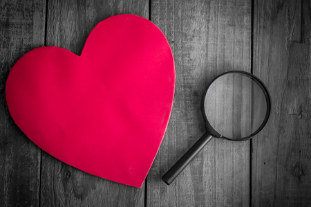 Read heart paper with magnifying glass on grunge wood tableの写真素材