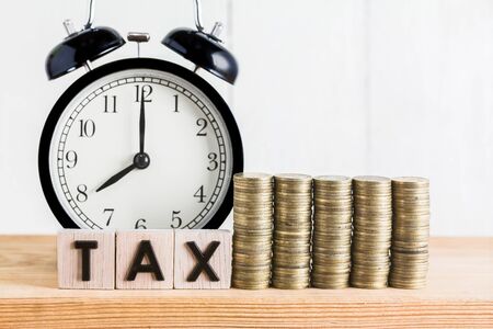 Stack of coins with tax letter in wooden block, Time to Saving for Tax Conceptの写真素材