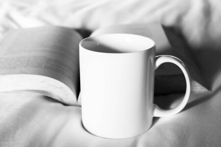 White cup with book on bed , black and white toneの写真素材