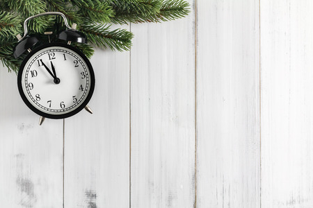 Christmas fir tree branches with alarm clock  on white rustic wooden background with copy space for...