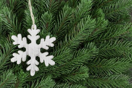 Wooden snowflake ornament on fir tree branches backgroundの写真素材