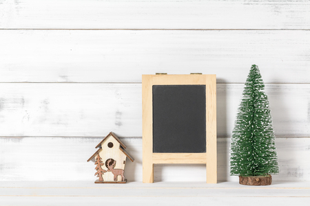 Blackboard and home ornament with christmas tree on white wood over white rustic background with copy space for textの写真素材