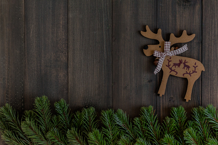 Christmas fir tree branches and reindeers on dark rustic wooden background with copy space for textの写真素材