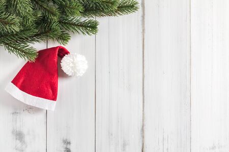 Christmas fir tree branches with santa claus hat  on white rustic wooden background with copy space for textの写真素材