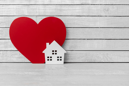 Home Shaped with Red Heart Shaped on white wood over white wood backgroundの写真素材