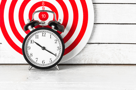 Dartboard with Alarm Clock on white wood.の写真素材