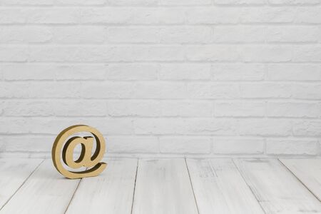 At sign on white wood table over white brick background with copy space.の写真素材