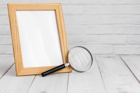 Photo frame and magnifying on white wood table with copy sapce, research concept.の写真素材