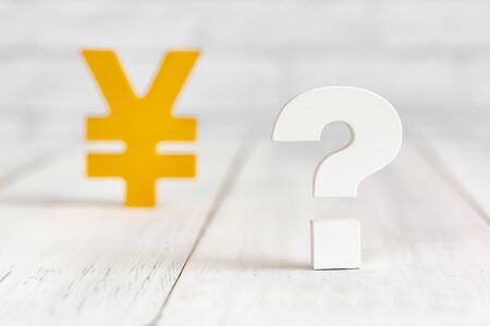 Question mark with yen sign on white wood table over white brick background with copy space.の写真素材